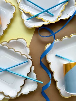 белые бумажные тарелки и стаканы с золотой каймой